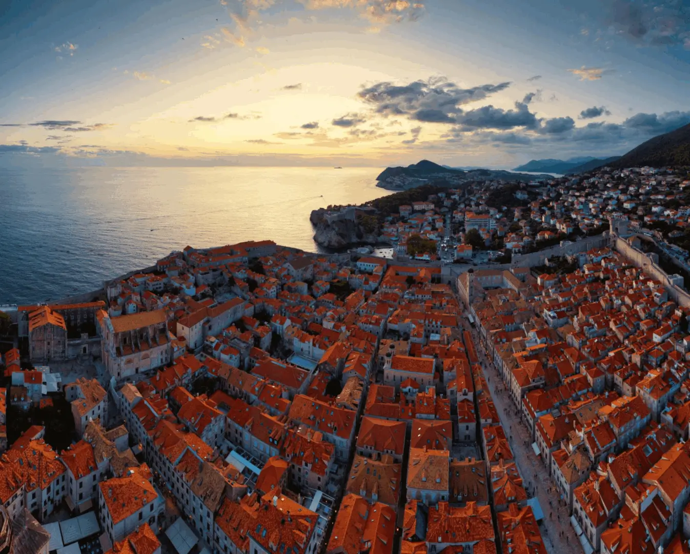 Golden sunset over orange-roofed coastal city
